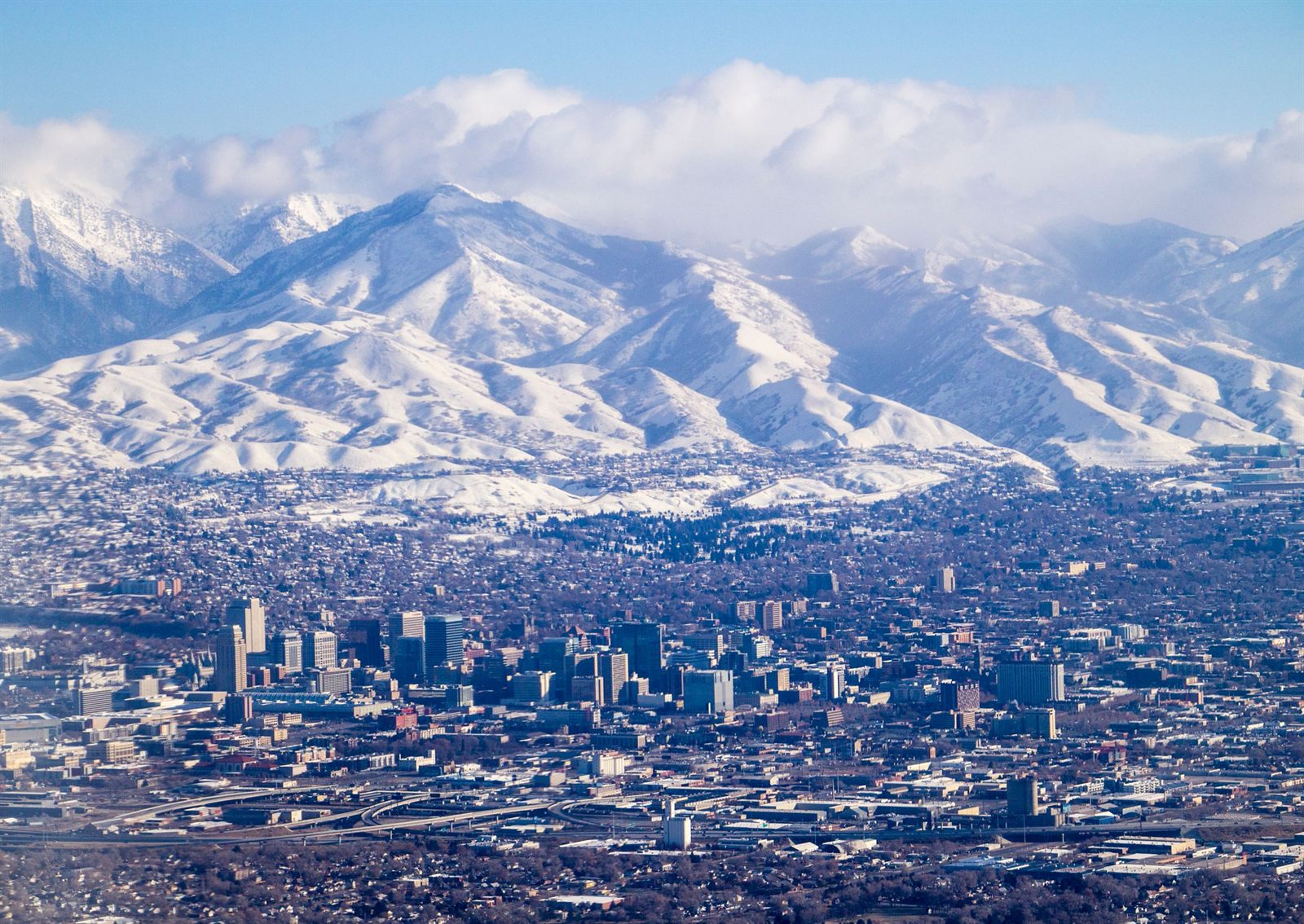 A city spread out below a long snow-covered mountain range